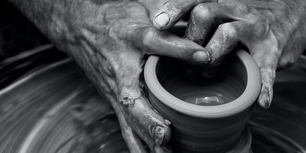 man throwing cup on pottery wheel