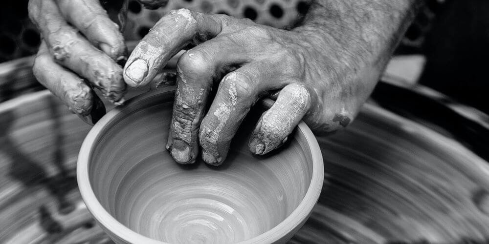 man throwing small bowl on pottery wheel